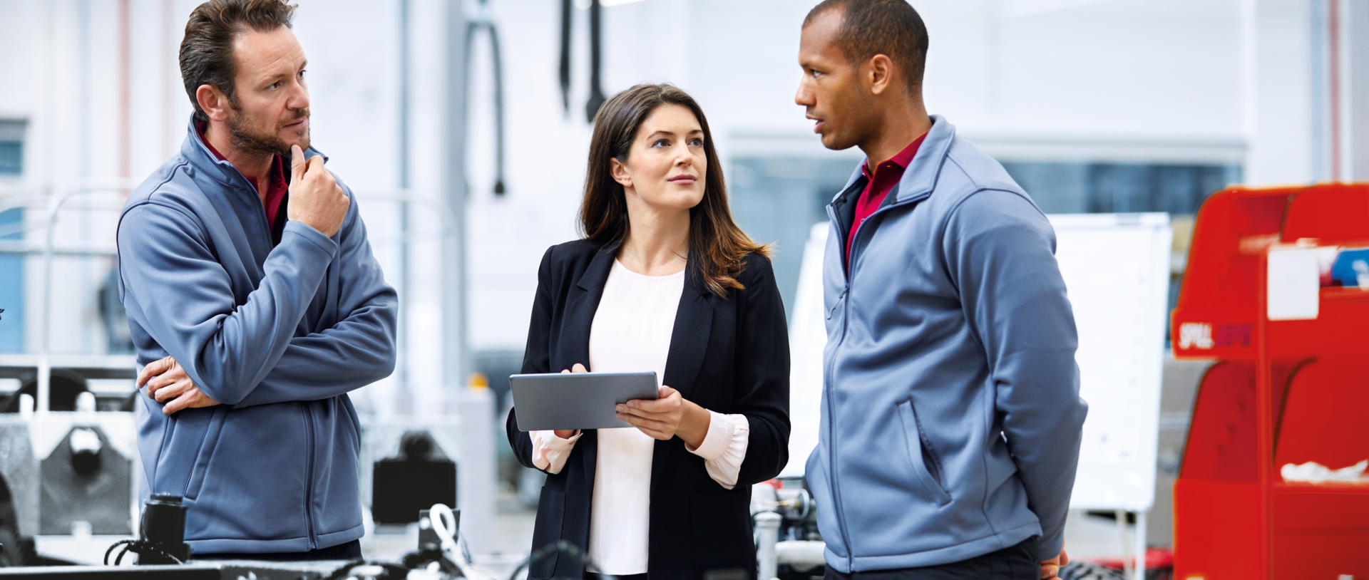 © iStock-913784122_Morsa Images (Automobile engineer discussing with colleagues in car factory. Multi-ethnic male and female professionals are standing at car production line. They are in automotive industry)