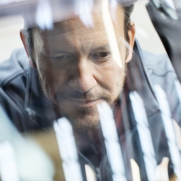 © iStock-916868472_Morsa Images (Close-up of male engineer seen through car windshield. Confident male is repairing vintage vehicle in automobile industry. Technologist is smiling while working in showroom.)